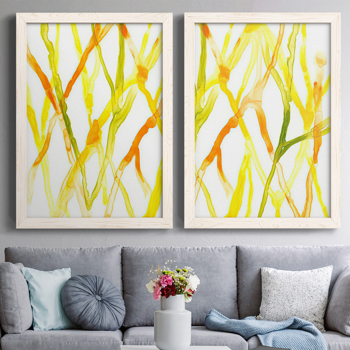 Set of two white barnwood framed canvas prints depicting paired fluid organic abstracts with slender vein-like strokes, transparent overlaps, and open negative space above a sofa in a contemporary living room.