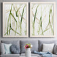 Set of two white barnwood framed canvas prints depicting paired fluid organic abstracts with slender vein-like strokes, transparent overlaps, and open negative space above a sofa in a contemporary living room.