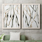 Set of two white barnwood framed canvas prints depicting a coordinated art pair of branching watercolor lines drifting across white rendered as fluid organic abstracts above a sofa in a modern living room.