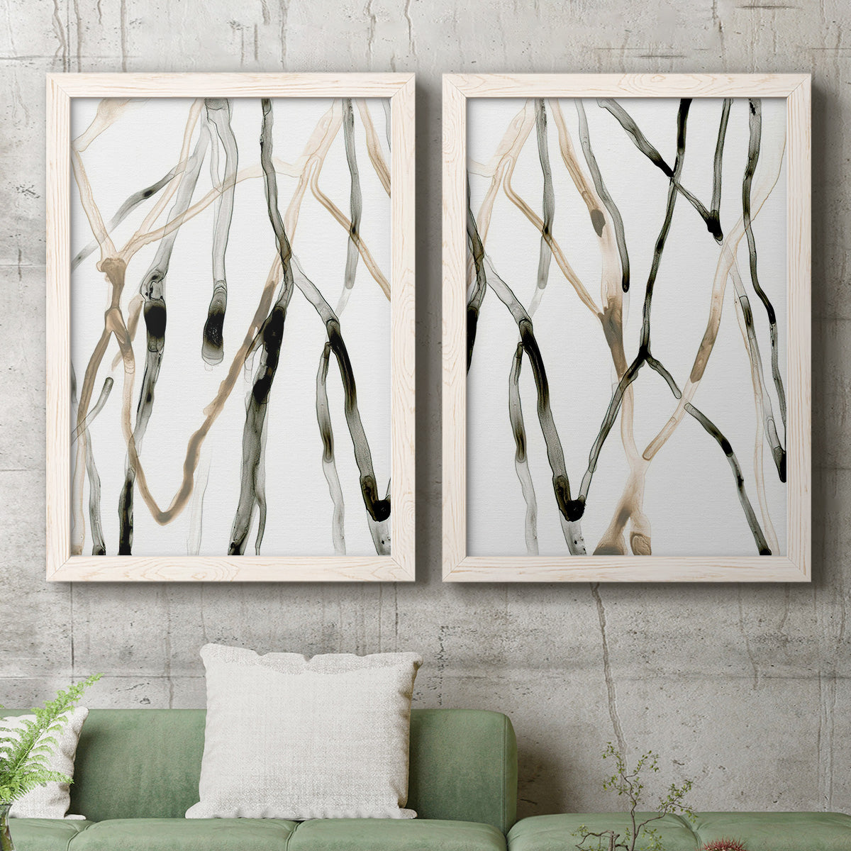 Set of two white barnwood framed canvas prints depicting a coordinated art pair of branching watercolor lines drifting across white rendered as fluid organic abstracts above a sofa in a modern living room.