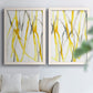 Set of two white barnwood framed canvas prints depicting slender vein-like strokes, transparent overlaps, and open negative space arranged across two complementary compositions above a sofa in a bright living space.