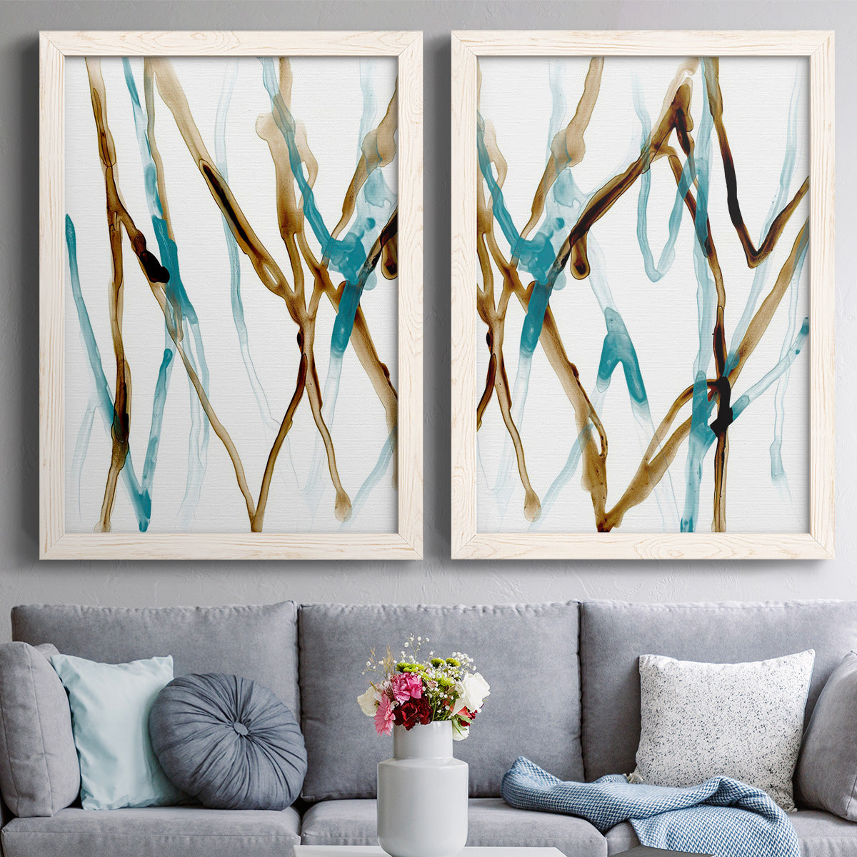 Set of two white barnwood framed canvas prints depicting delicate runnels of teal and earth tones creating loose branchlike patterns across two panels above a sofa in a contemporary living room.