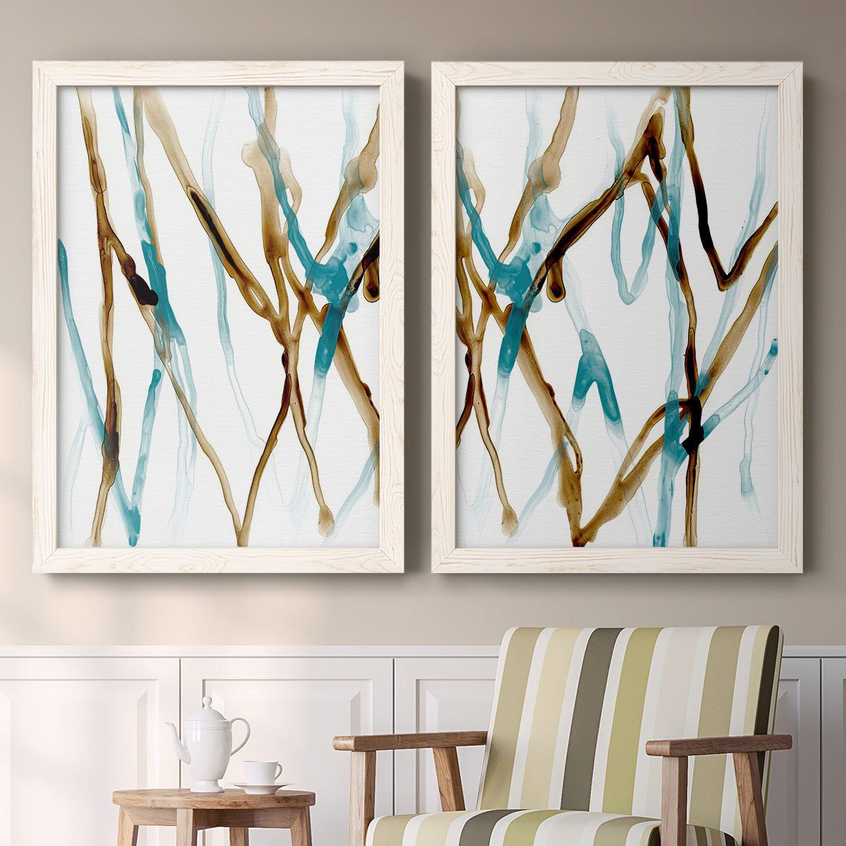 Set of two white barnwood framed canvas prints depicting two fluid abstracts with branching turquoise and brown lines drifting across white backgrounds above a sideboard in a cozy sitting room.