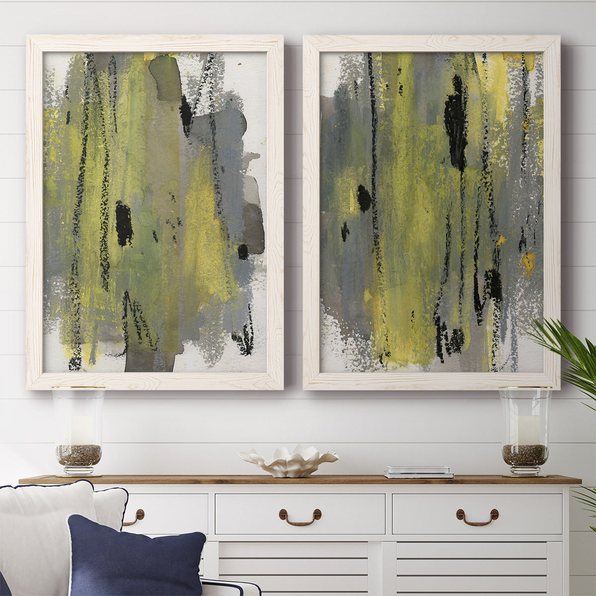 Set of two white barnwood framed canvas prints depicting a coordinated art pair of vertical abstract brush bands in changing muted palettes rendered as urban mixed-media abstracts above a dining room sideboard.
