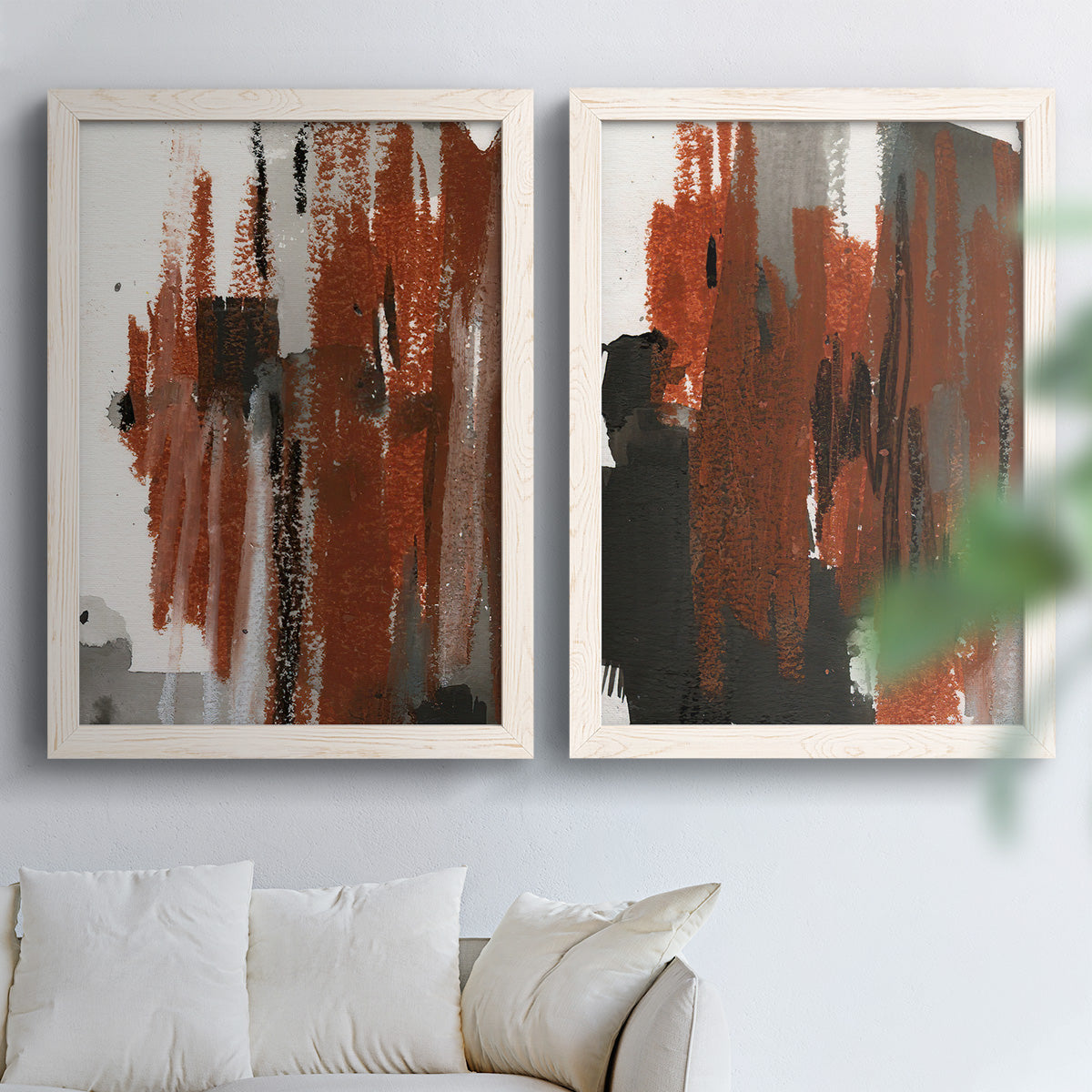 Set of two white barnwood framed canvas prints depicting scraped paint, black accents, and layered gray green rust or yellow fields arranged across two complementary compositions above a sofa in a bright living space.