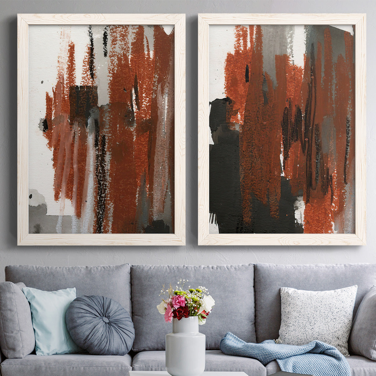 Set of two white barnwood framed canvas prints depicting paired urban mixed-media abstracts with scraped paint, black accents, and layered gray green rust or yellow fields above a sofa in a contemporary living room.