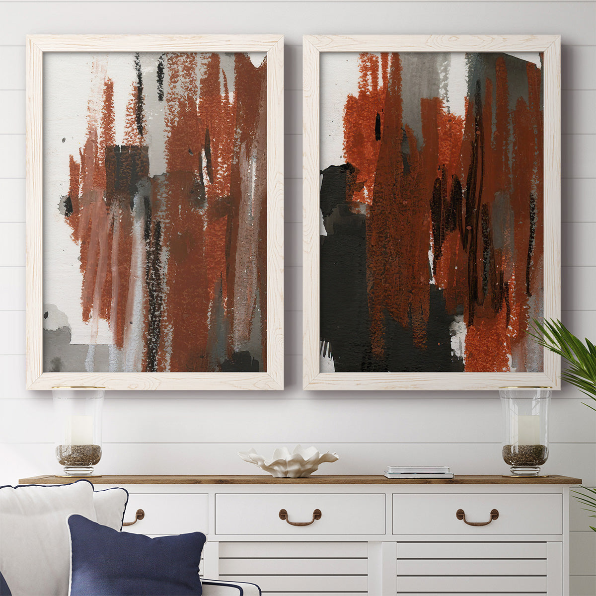 Set of two white barnwood framed canvas prints depicting a coordinated art pair of vertical abstract brush bands in changing muted palettes rendered as urban mixed-media abstracts above a dining room sideboard.