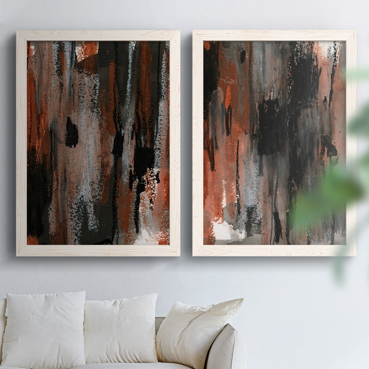 Set of two white barnwood framed canvas prints depicting scraped paint, black accents, and layered gray green rust or yellow fields arranged across two complementary compositions above a sofa in a bright living space.