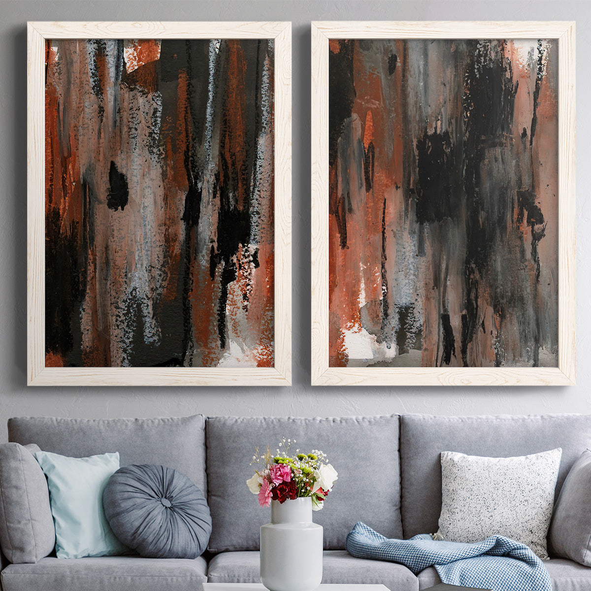 Set of two white barnwood framed canvas prints depicting paired urban mixed-media abstracts with scraped paint, black accents, and layered gray green rust or yellow fields above a sofa in a contemporary living room.