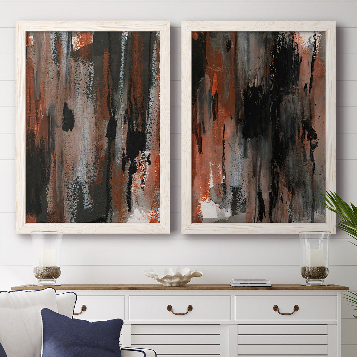 Set of two white barnwood framed canvas prints depicting a coordinated art pair of vertical abstract brush bands in changing muted palettes rendered as urban mixed-media abstracts above a dining room sideboard.