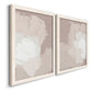 Angled view of a set of two white barnwood framed canvas prints featuring two neutral minimalist abstracts featuring soft taupe blush and white paint blocks.