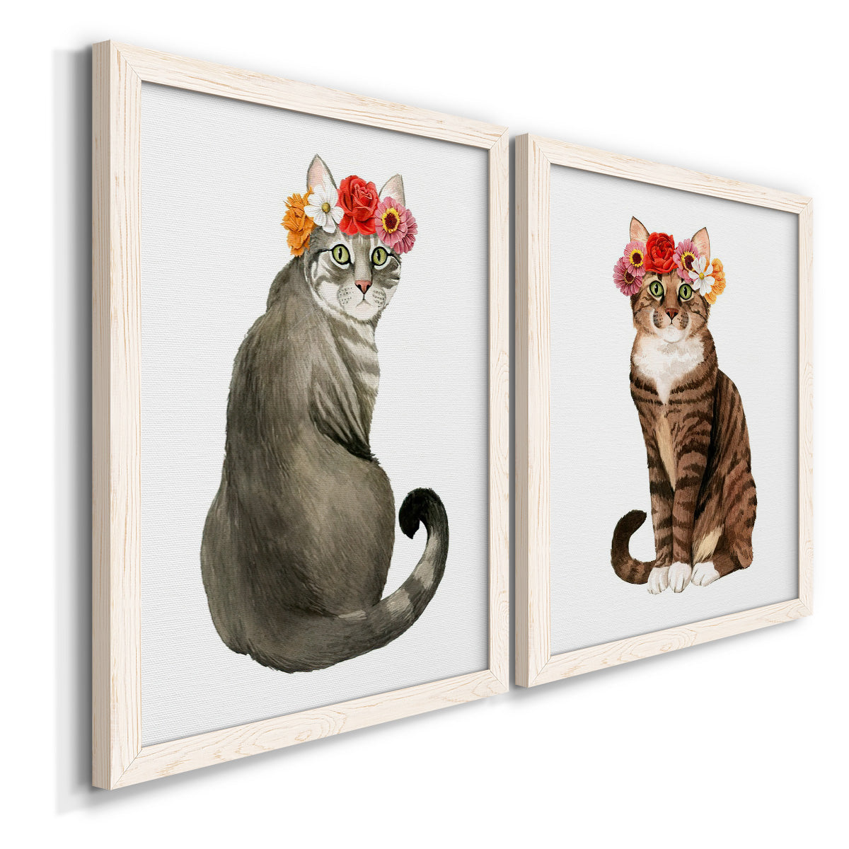 Angled view of a set of two white barnwood framed canvas prints featuring two whimsical animal portraits featuring seated cats wearing colorful flower crowns.