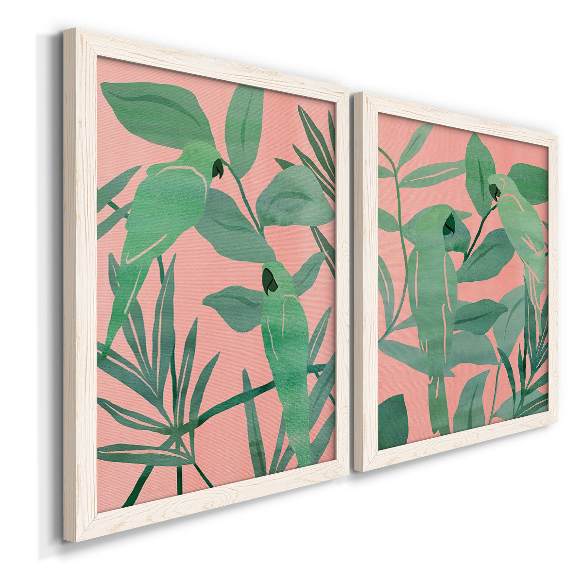 Angled view of a set of two white barnwood framed canvas prints featuring two bold tropical botanical prints featuring large green tropical leaves on coral-pink grounds.