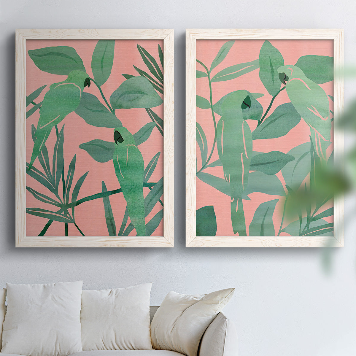 Set of two white barnwood framed canvas prints depicting overlapping foliage, flat graphic shapes, and high-contrast color arranged across two complementary compositions above a sofa in a bright living space.