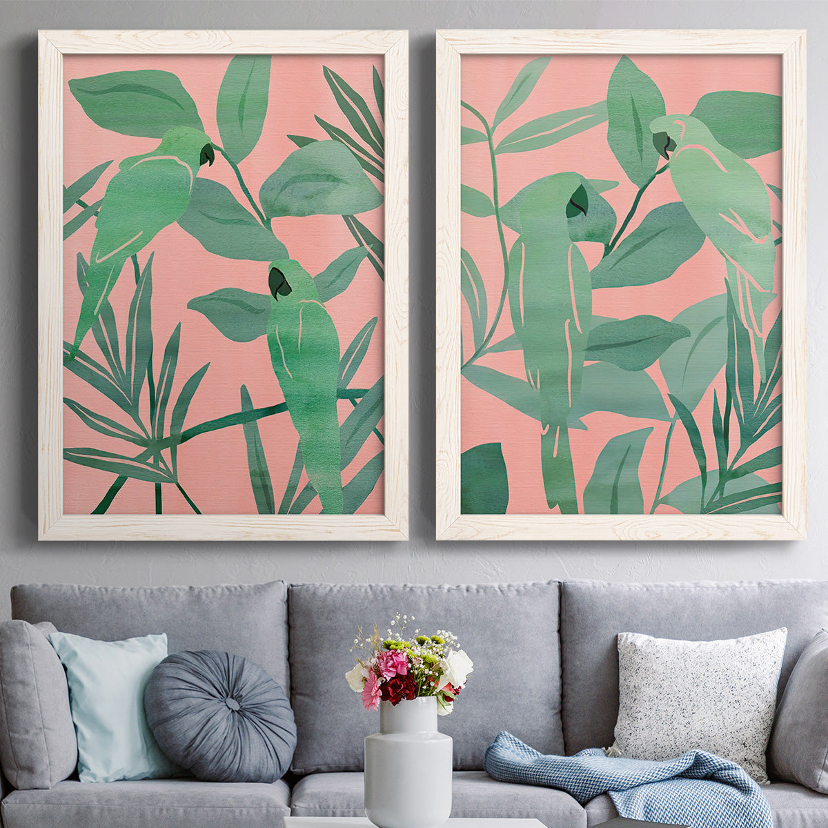 Set of two white barnwood framed canvas prints depicting paired bold tropical botanical prints with overlapping foliage, flat graphic shapes, and high-contrast color above a sofa in a contemporary living room.