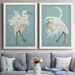 Set of two white barnwood framed canvas prints depicting paired decorative bird illustrations with elegant wading birds, sweeping plumage, and solid olive blue or ochre grounds above a sofa in a contemporary living room.