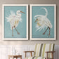Set of two white barnwood framed canvas prints depicting two decorative bird illustrations featuring white herons displaying long windswept feathers above a sideboard in a cozy sitting room.
