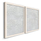 Angled view of a set of two white barnwood framed canvas prints featuring two textural monochrome abstracts featuring overlapping white carved arcs and ridges.