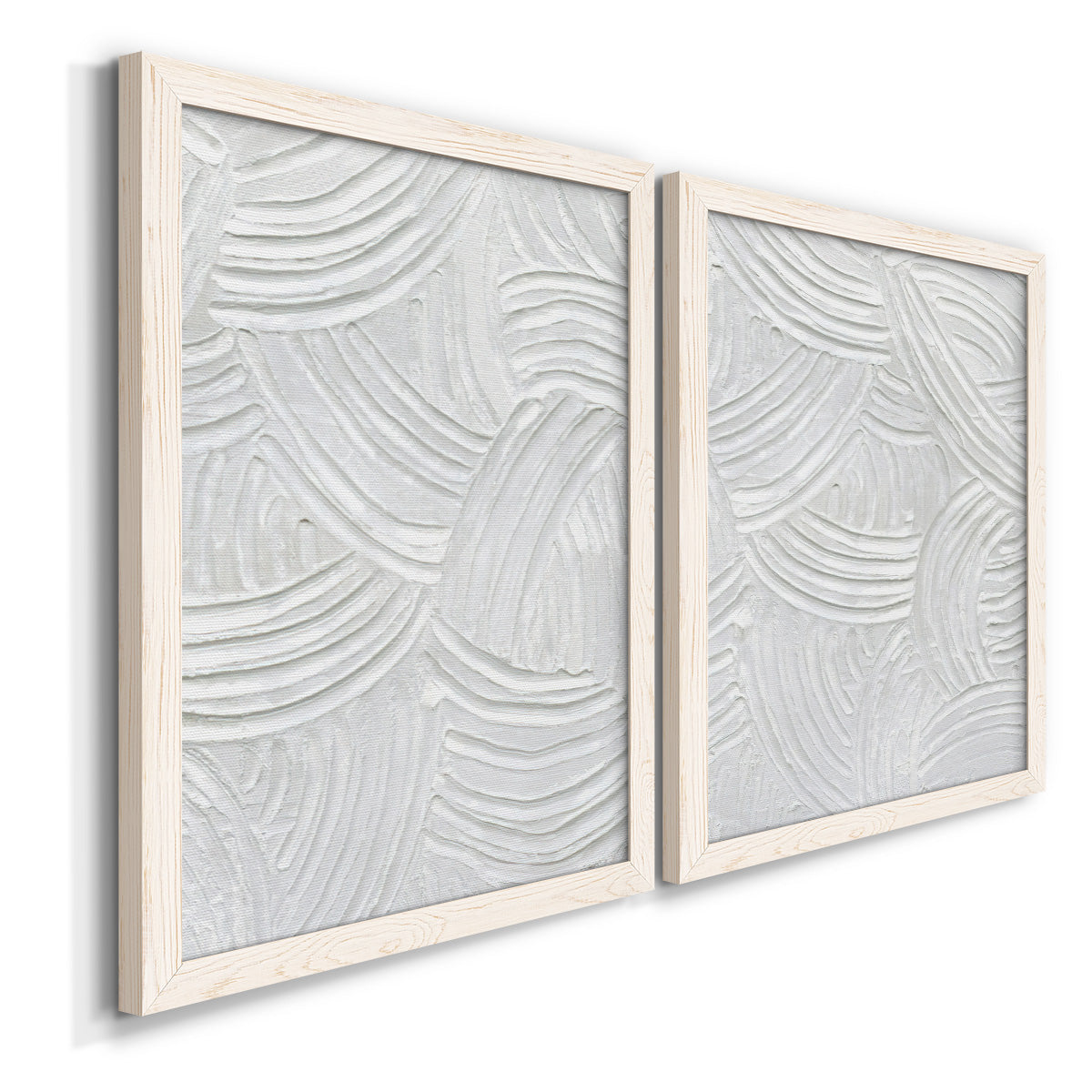 Angled view of a set of two white barnwood framed canvas prints featuring two textural monochrome abstracts featuring overlapping white carved arcs and ridges.