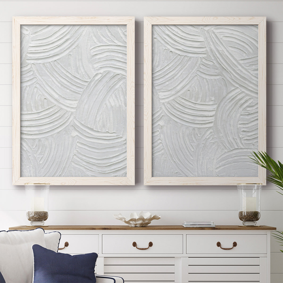Set of two white barnwood framed canvas prints depicting a coordinated art pair of overlapping white carved arcs and ridges rendered as textural monochrome abstracts above a dining room sideboard.