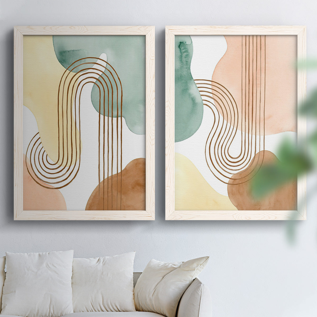 Set of two white barnwood framed canvas prints depicting stylized bouquets, blue block-print forms, and warm white grounds arranged across two complementary compositions above a sofa in a bright living space.