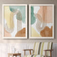 Set of two white barnwood framed canvas prints depicting two folk-inspired botanical patterns featuring repeating indigo floral and leaf motifs above a sideboard in a cozy sitting room.