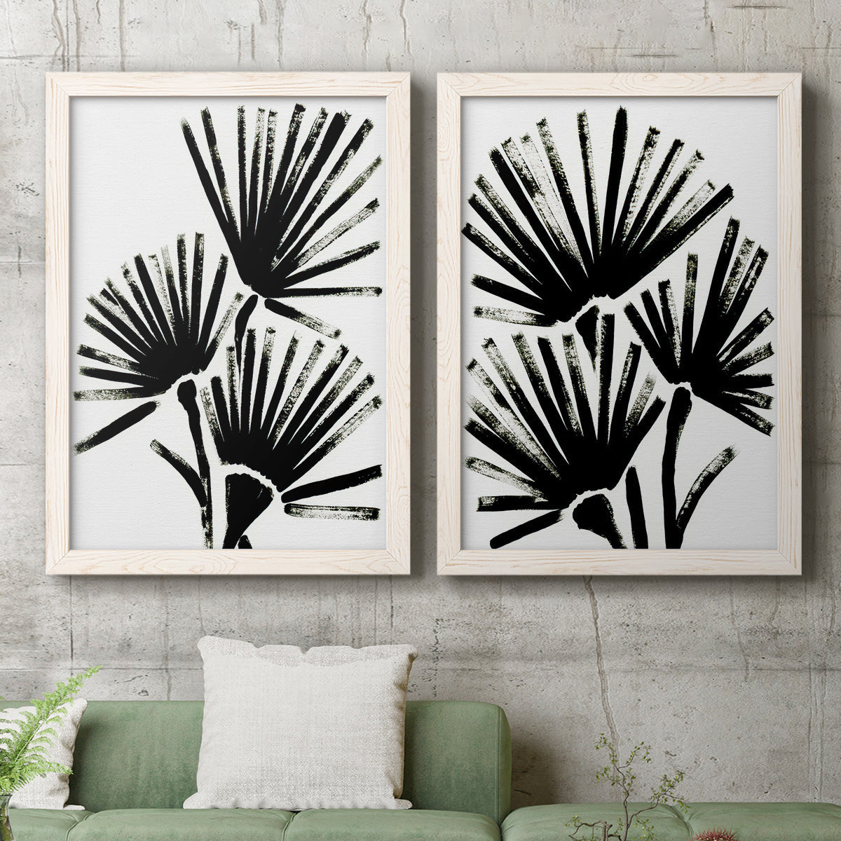 Set of two white barnwood framed canvas prints depicting a coordinated art pair of black fan-shaped botanical forms rendered as bold monochrome botanical prints above a sofa in a modern living room.