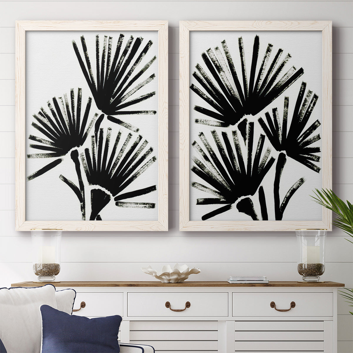 Set of two white barnwood framed canvas prints depicting a coordinated art pair of black fan-shaped botanical forms rendered as bold monochrome botanical prints above a dining room sideboard.