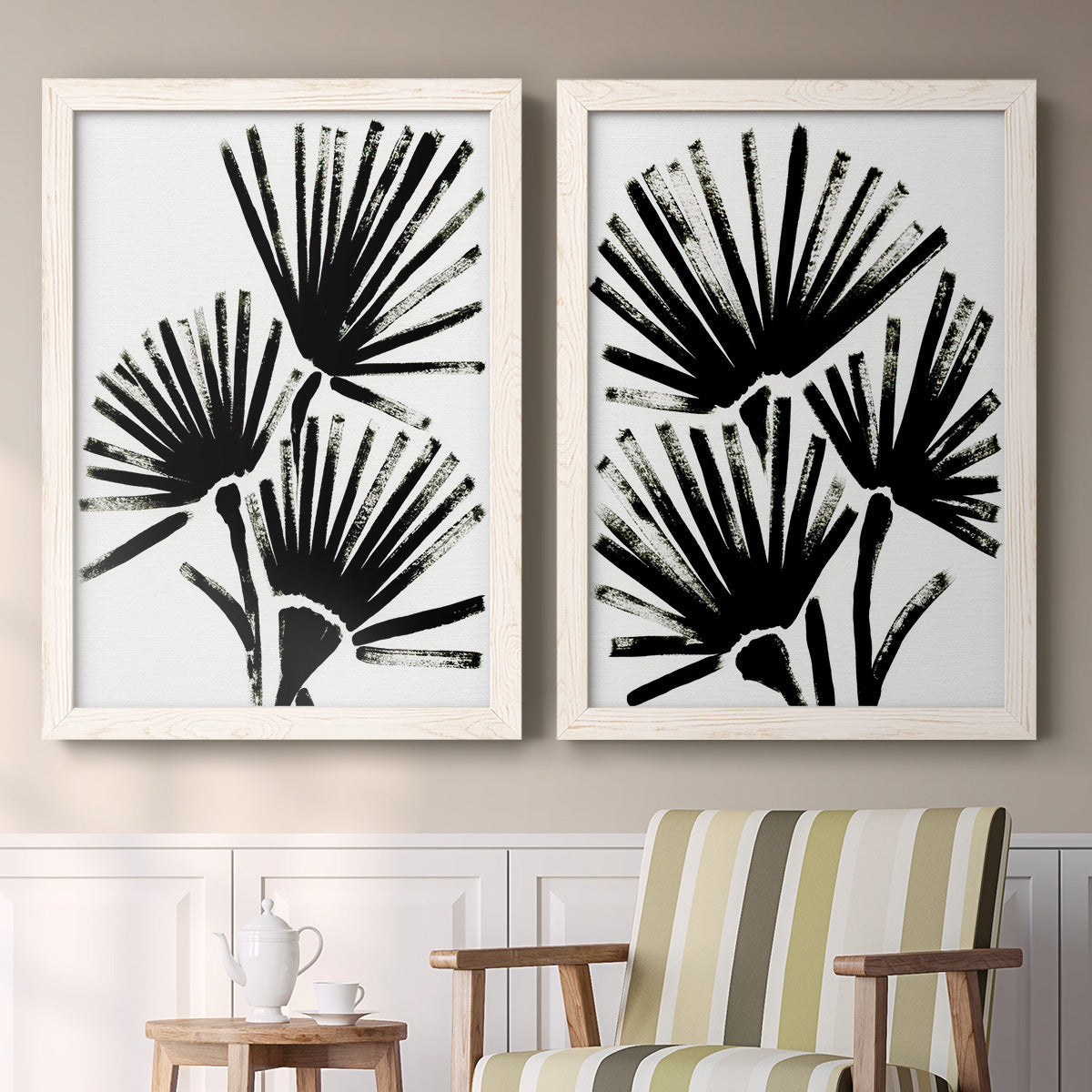 Set of two white barnwood framed canvas prints depicting two bold monochrome botanical prints featuring black fan-shaped botanical forms above a sideboard in a cozy sitting room.