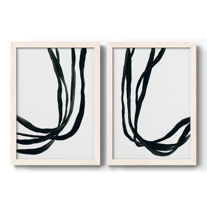 Set of two white barnwood framed canvas prints featuring two minimalist gestural line abstracts featuring flowing black ribbon-like lines.