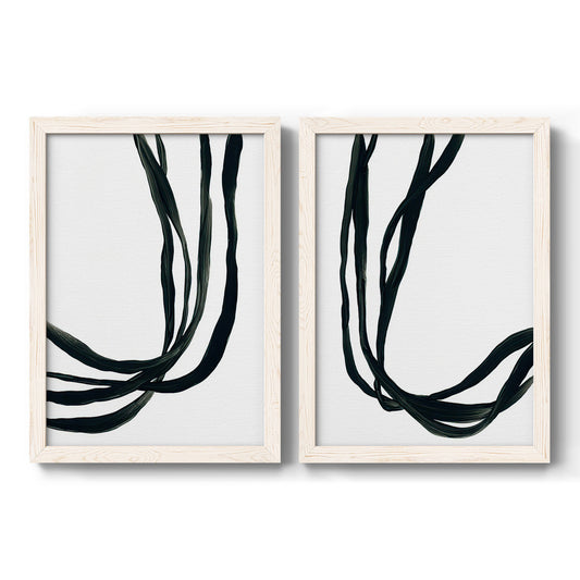 Set of two white barnwood framed canvas prints featuring two minimalist gestural line abstracts featuring flowing black ribbon-like lines.