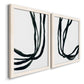 Angled view of a set of two white barnwood framed canvas prints featuring two minimalist gestural line abstracts featuring flowing black ribbon-like lines.