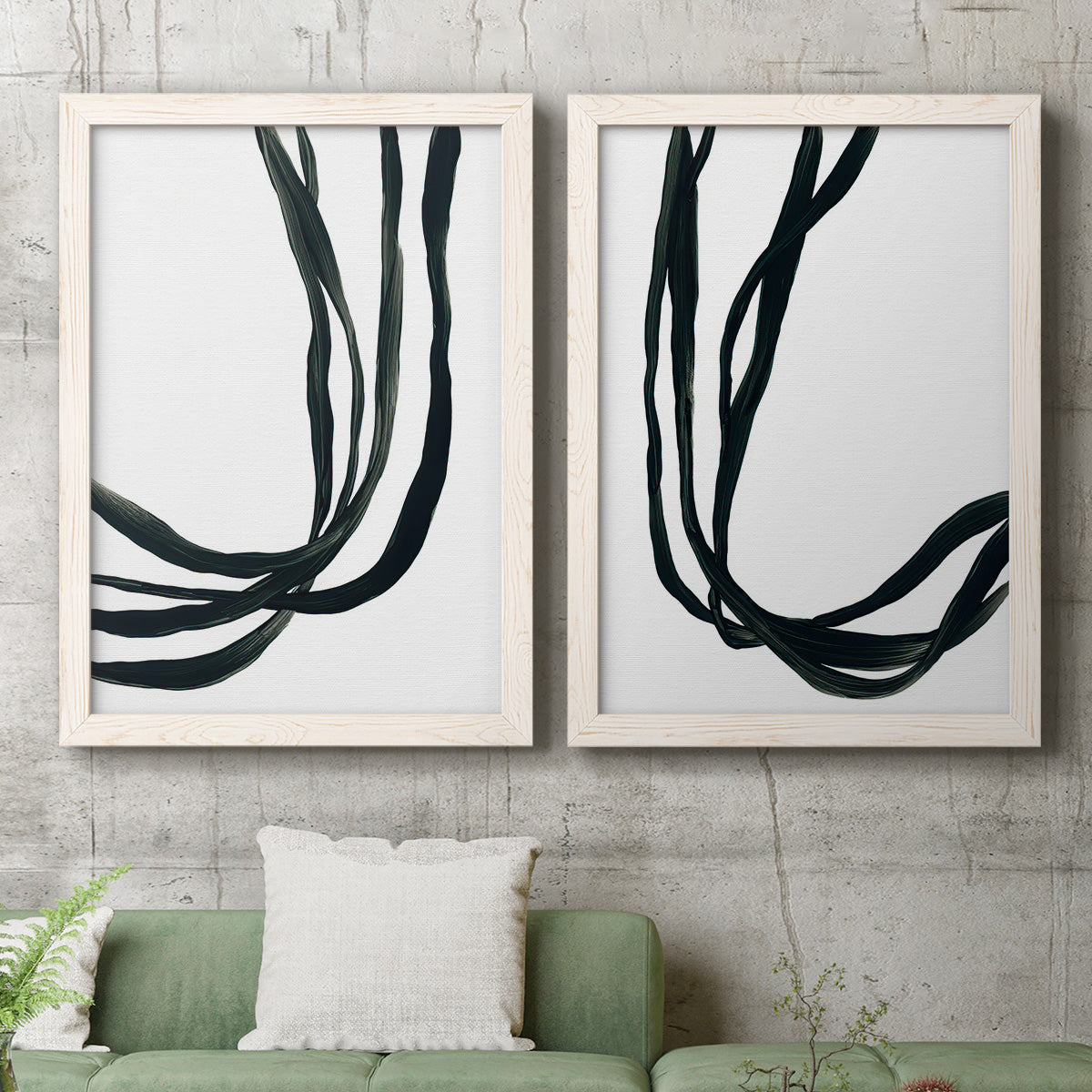 Set of two white barnwood framed canvas prints depicting a coordinated art pair of flowing black ribbon-like lines rendered as minimalist gestural line abstracts above a sofa in a modern living room.