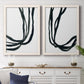 Set of two white barnwood framed canvas prints depicting a coordinated art pair of flowing black ribbon-like lines rendered as minimalist gestural line abstracts above a dining room sideboard.