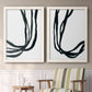 Set of two white barnwood framed canvas prints depicting two minimalist gestural line abstracts featuring flowing black ribbon-like lines above a sideboard in a cozy sitting room.
