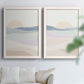 Set of two white barnwood framed canvas prints depicting soft blue lavender beige and cream bands with a simple horizon arranged across two complementary compositions above a sofa in a bright living space.