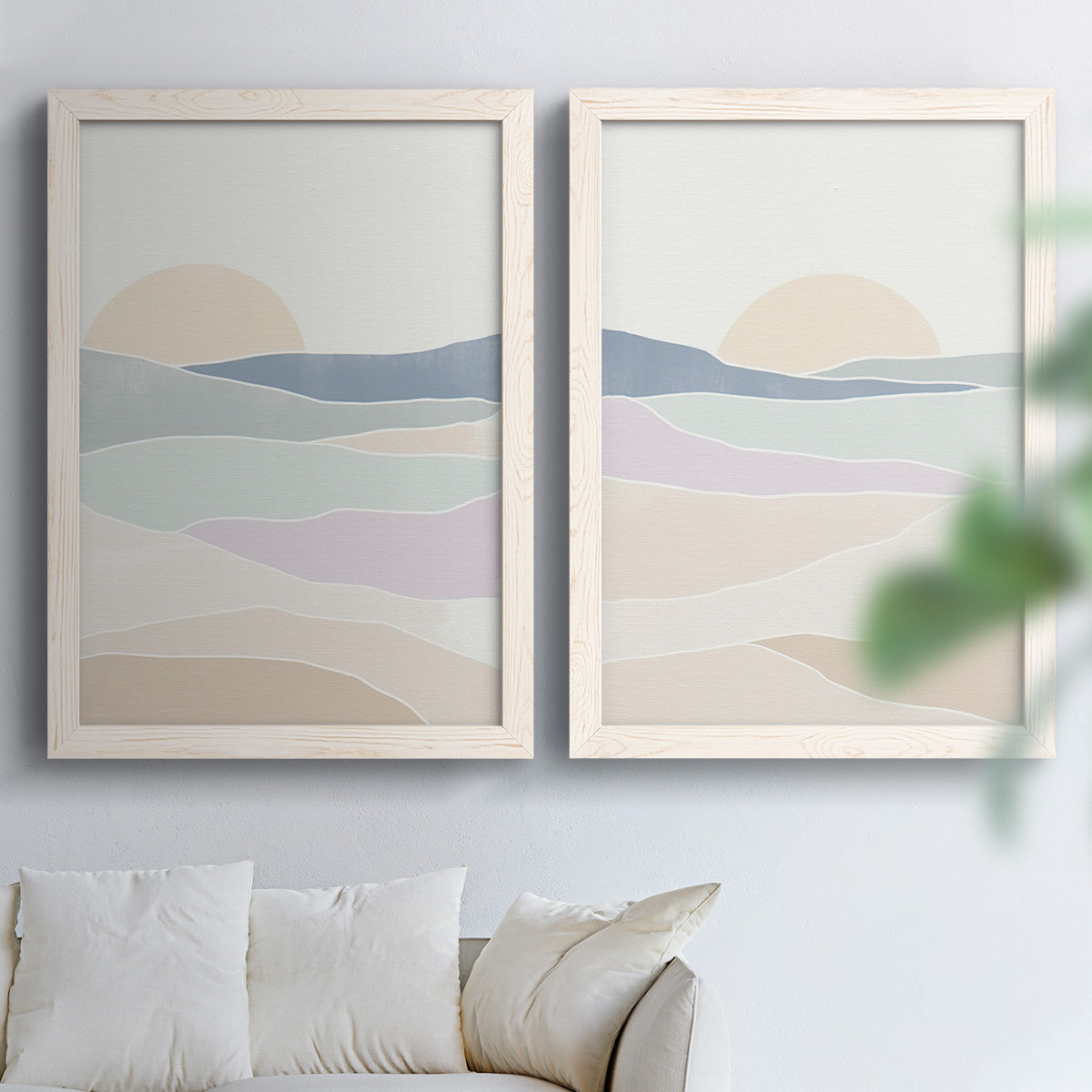 Set of two white barnwood framed canvas prints depicting soft blue lavender beige and cream bands with a simple horizon arranged across two complementary compositions above a sofa in a bright living space.
