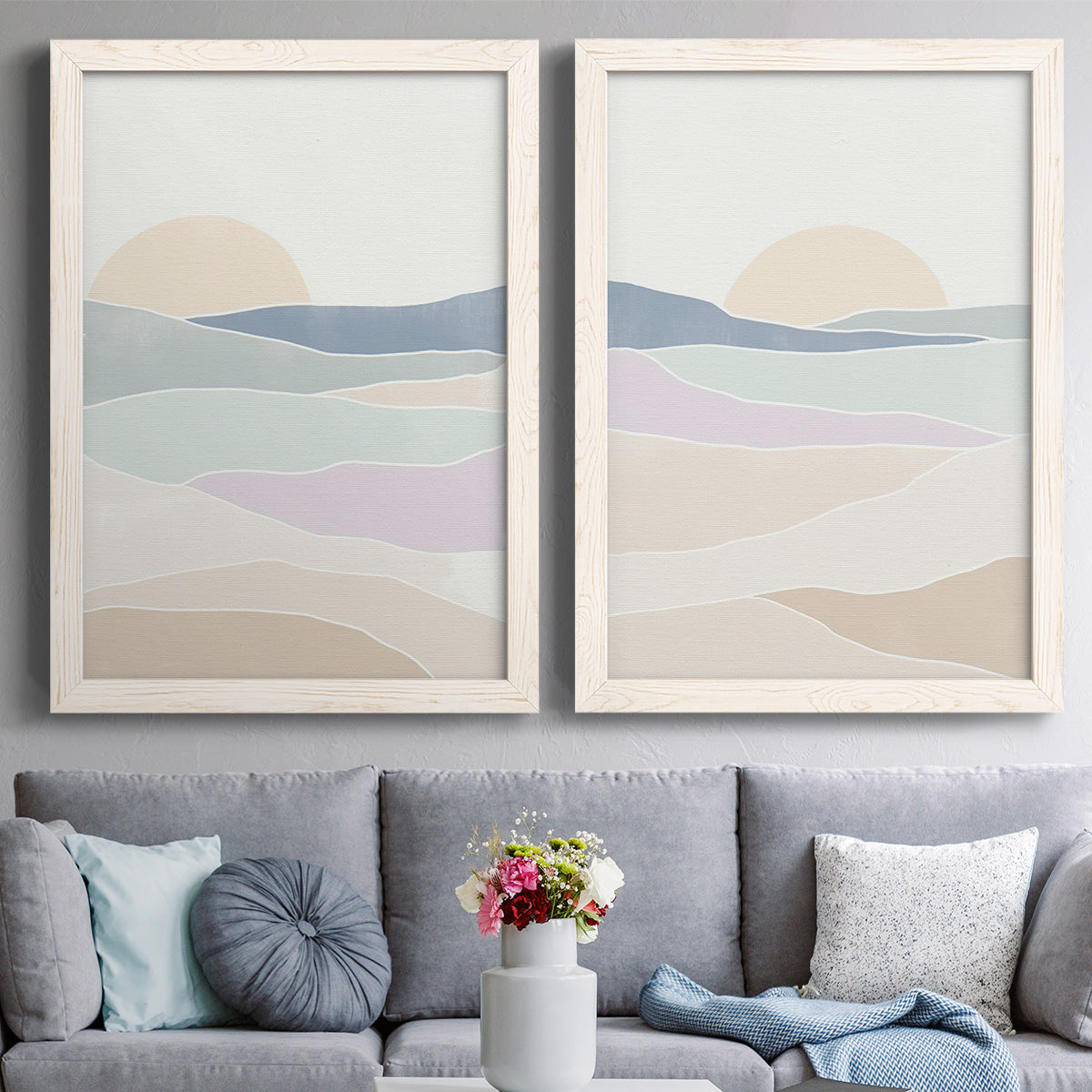 Set of two white barnwood framed canvas prints depicting paired minimalist abstract landscapes with soft blue lavender beige and cream bands with a simple horizon above a sofa in a contemporary living room.