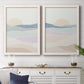 Set of two white barnwood framed canvas prints depicting a coordinated art pair of layered pastel waves beneath a pale setting sun rendered as minimalist abstract landscapes above a dining room sideboard.