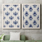 Set of two white barnwood framed canvas prints depicting a coordinated botanical print pair featuring navy flower motifs in orderly repeating layouts above a sofa in a modern living room.