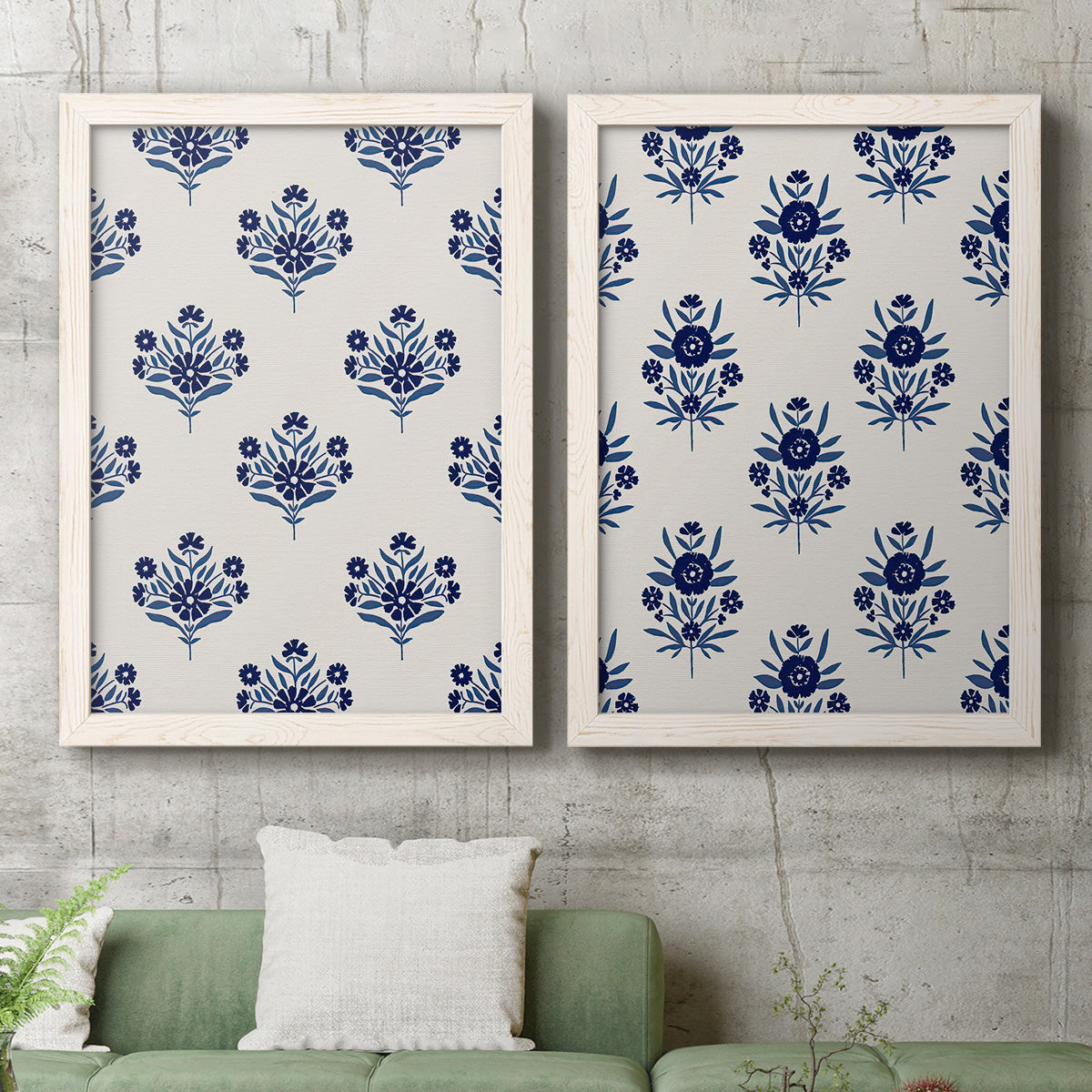 Set of two white barnwood framed canvas prints depicting a coordinated botanical print pair featuring navy flower motifs in orderly repeating layouts above a sofa in a modern living room.