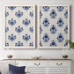 Set of two white barnwood framed canvas prints depicting a coordinated botanical print pair featuring navy flower motifs in orderly repeating layouts above a dining room sideboard.