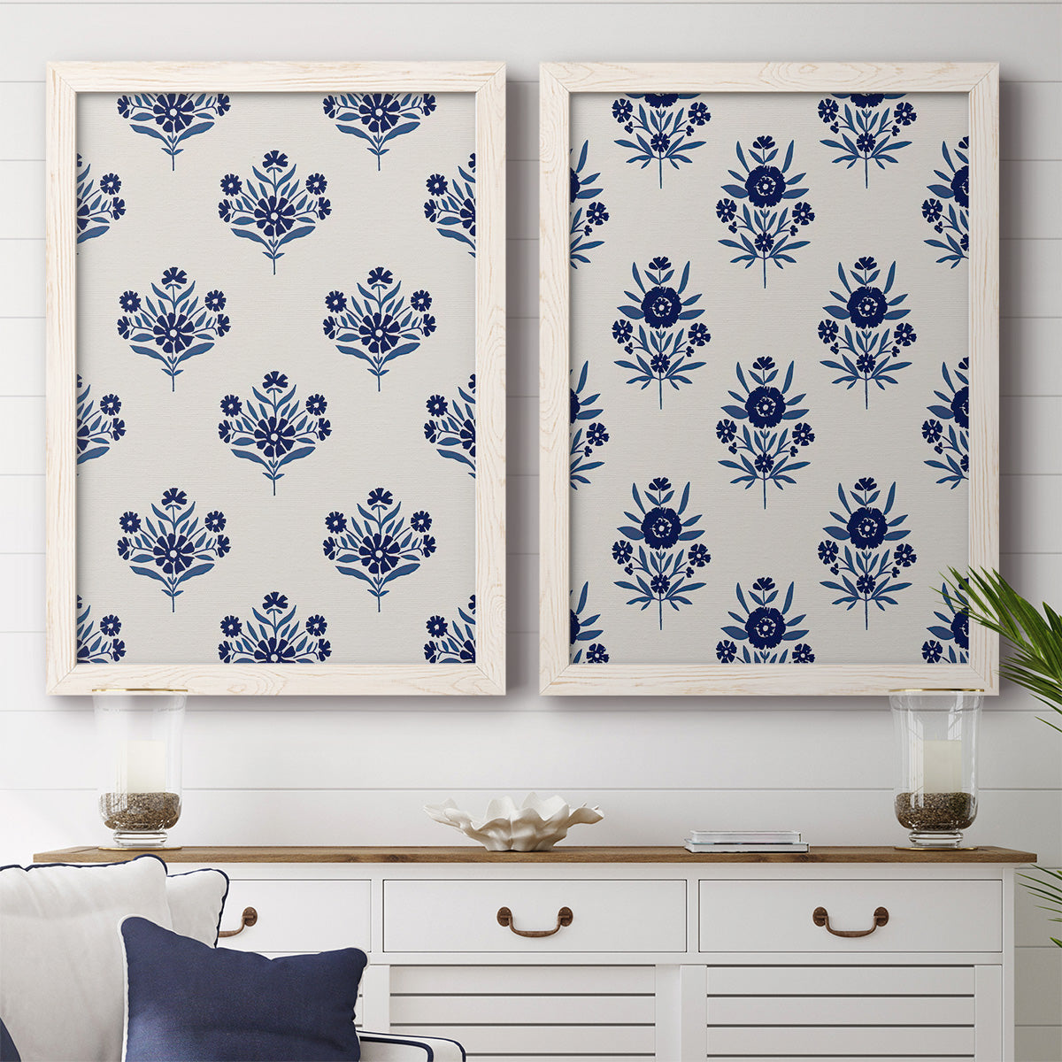 Set of two white barnwood framed canvas prints depicting a coordinated botanical print pair featuring navy flower motifs in orderly repeating layouts above a dining room sideboard.