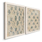 Angled view of a set of two white barnwood framed canvas prints featuring two weathered block-print patterns featuring small repeating blue floral motifs.
