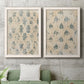 Set of two white barnwood framed canvas prints depicting a coordinated art pair of small repeating blue floral motifs rendered as weathered block-print patterns above a sofa in a modern living room.