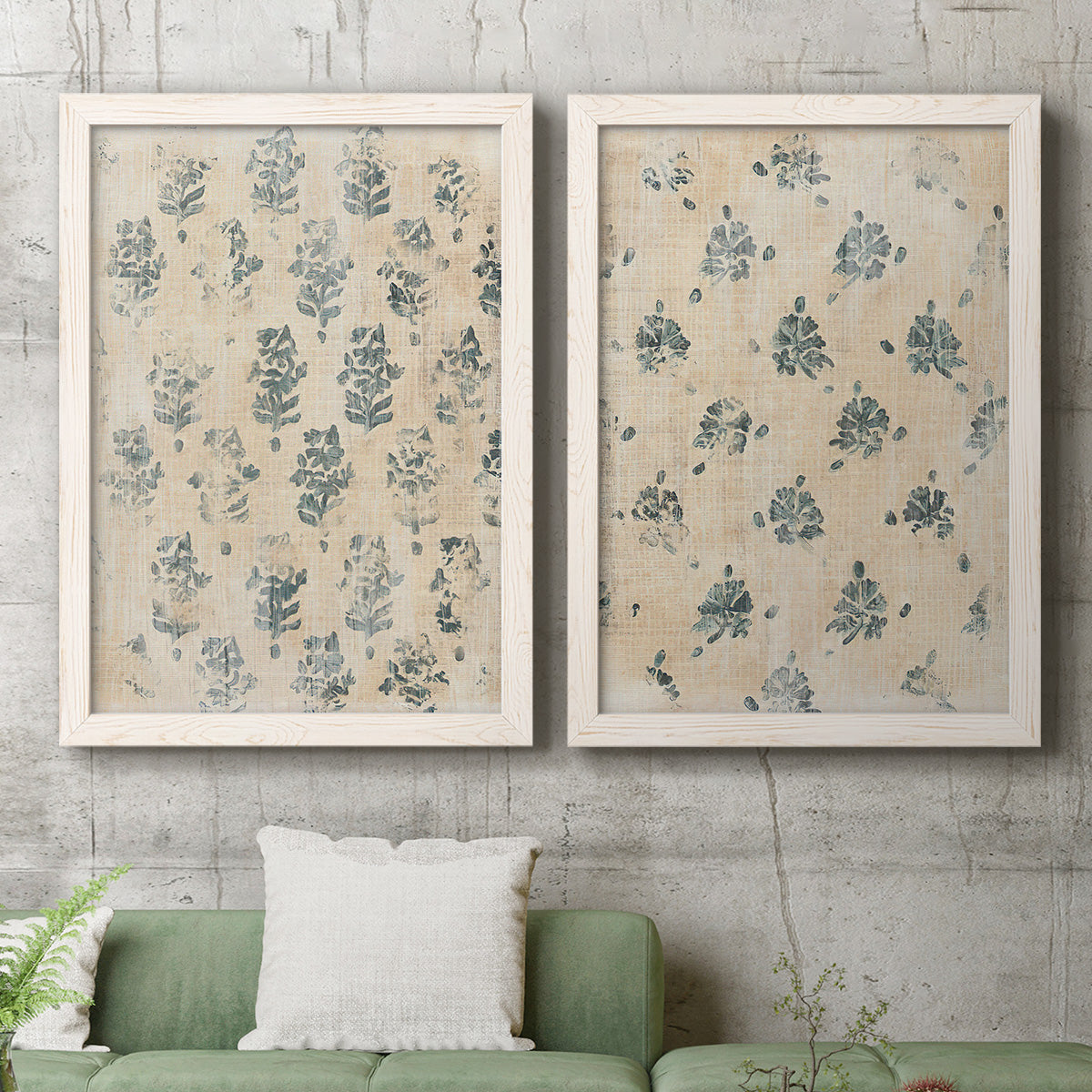 Set of two white barnwood framed canvas prints depicting a coordinated art pair of small repeating blue floral motifs rendered as weathered block-print patterns above a sofa in a modern living room.