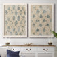 Set of two white barnwood framed canvas prints depicting a coordinated art pair of small repeating blue floral motifs rendered as weathered block-print patterns above a dining room sideboard.