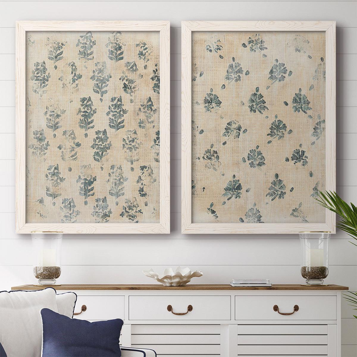 Set of two white barnwood framed canvas prints depicting a coordinated art pair of small repeating blue floral motifs rendered as weathered block-print patterns above a dining room sideboard.