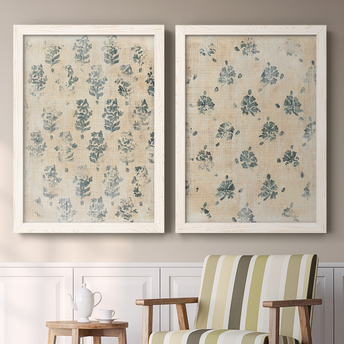 Set of two white barnwood framed canvas prints depicting two weathered block-print patterns featuring small repeating blue floral motifs above a sideboard in a cozy sitting room.