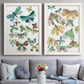 Set of two white barnwood framed canvas prints depicting paired decorative insect illustrations with patterned wings, leafy accents, and softly vintage natural-history styling above a sofa in a contemporary living room.
